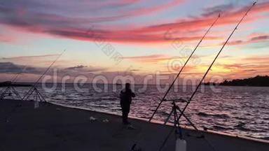 渔人剪影在日落时烤鱼竿.